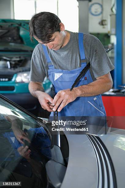 germany, ebenhausen, mechatronic technician working in car garage - ruitenwisser stockfoto's en -beelden