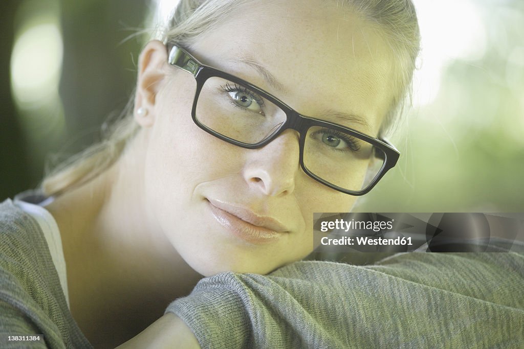 Germany, Bavaria, Schaeftlarn, Young woman wearing thick rimmed spectacles, smiling, portrait, close up