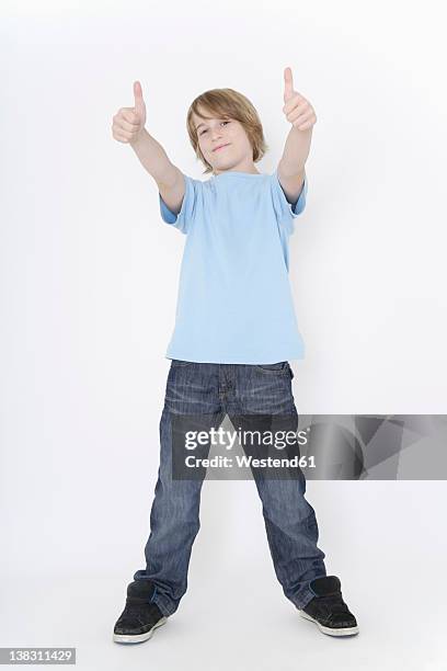 germany, bavaria, ebenhausen, boy standing against white background, smiling - pouce levé fond blanc photos et images de collection