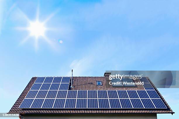 germany, solar panels on houseroof in front of blue sky with sun - ソーラー設備 ストックフォトと画像