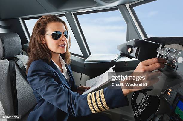 germany, bavaria, munich, woman flight captain with map in airplane cockpit - pilotenbrille stock-fotos und bilder