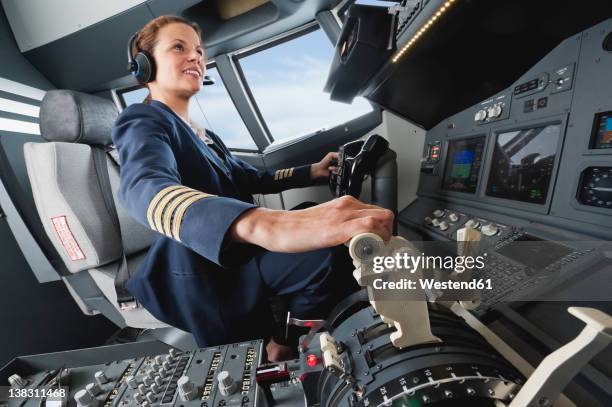 germany, bavaria, munich, woman flight captain piloting aeroplane from airplane cockpit - pilotar fotografías e imágenes de stock