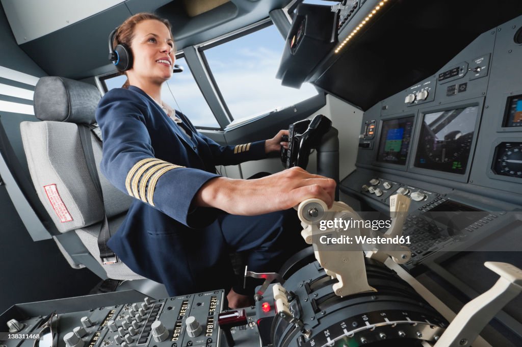 Germany, Bavaria, Munich, Woman flight captain piloting aeroplane from airplane cockpit