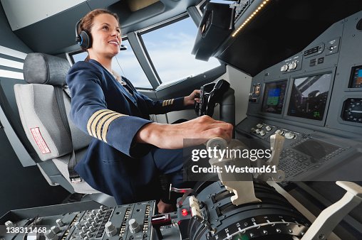 Germany, Bavaria, Munich, Woman flight captain piloting aeroplane from airplane cockpit Germany, Bavaria, Munich, Woman flight captain piloting aeroplane from airplane cockpit