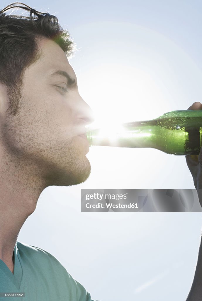 Spain, Majorca, Young man drinking beer, close up