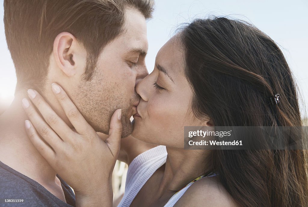 Spain, Majorca, Young couple kissing on boardwalk, close up