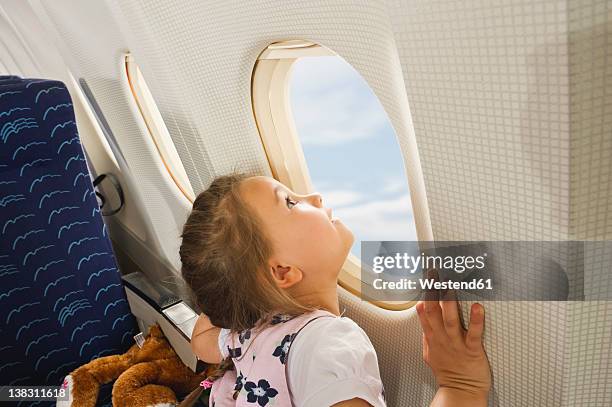 germany, munich, bavaria, girl looking through window in economy class airliner - airplane seat stock pictures, royalty-free photos & images