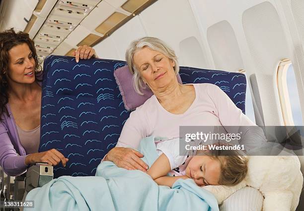 germany, munich, bavaria, senior woman and girl sleeping beside window in economy class airliner - grandma sleeping stockfoto's en -beelden