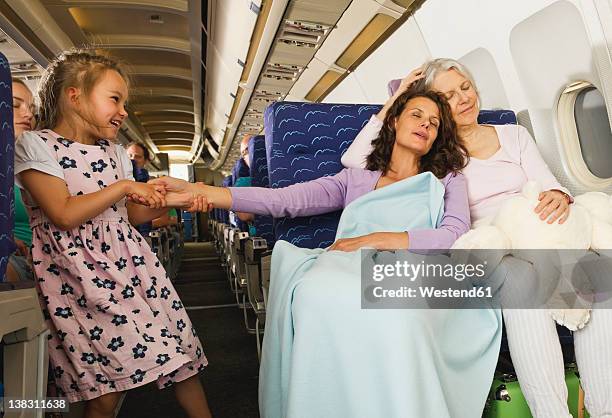germany, munich, bavaria, women sleeping and girl pulling woman's hand in economy class airliner - grandma sleeping stockfoto's en -beelden