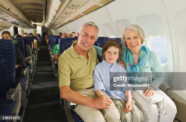 germany, munich, bavaria, boy sitting besides senior people in economy class airliner - flugzeugsitz stock-fotos und bilder