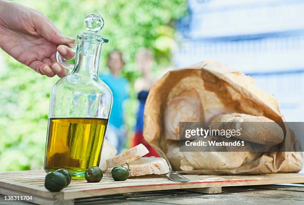 italy, tuscany, magliano, close up of bread, olive oil and olives on wooden table - cruet stock pictures, royalty-free photos & images