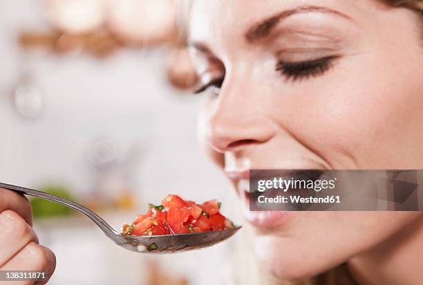 italy, tuscany, magliano, young woman eating spoon of chopped tomatoes, smiling - brot mund stock-fotos und bilder