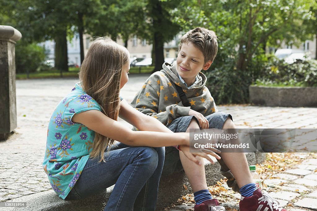 Germany, Berlin, Boy and girl sitting on curbstone