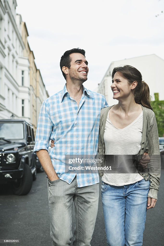 Germany, Berlin, Couple walking hand in hand through city street