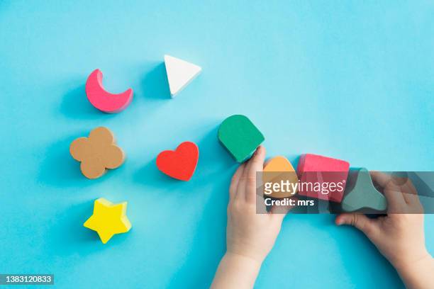 toddler is playing with a wooden toy block - kid hand raised stock pictures, royalty-free photos & images