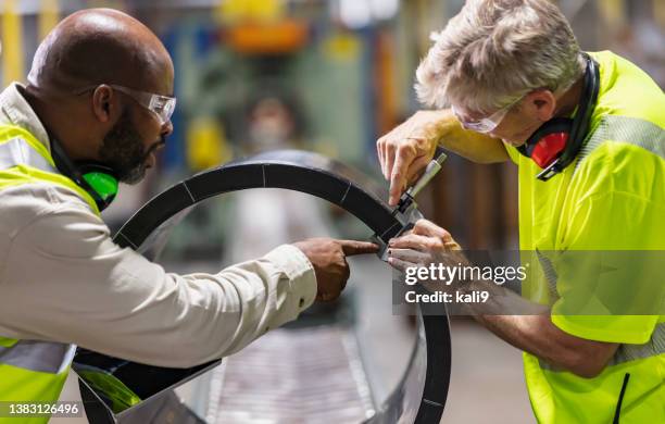 zwei multirassische arbeiter in der fabrik am fließband - calipers stock-fotos und bilder