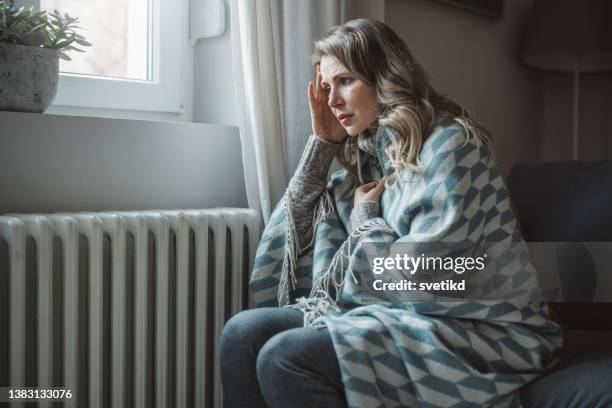 unwell woman feel cold in home with no heating - ac weary stockfoto's en -beelden