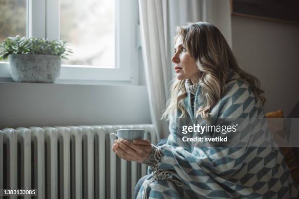 la donna malata si sente fredda in casa senza riscaldamento - freddo foto e immagini stock
