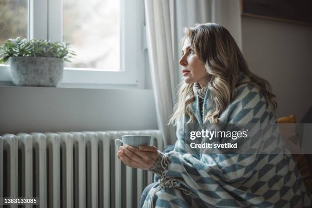 la donna malata si sente fredda in casa senza riscaldamento - brivido foto e immagini stock