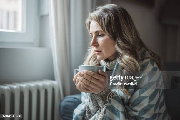 unwell woman feel cold in home with no heating - ac weary stockfoto's en -beelden