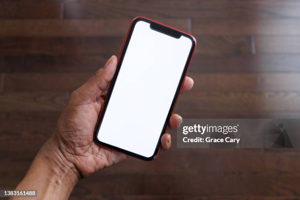 woman holds smart phone with blank screen - holding iphone screen stock pictures, royalty-free photos & images