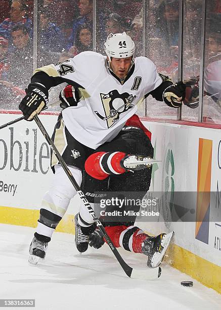 Brooks Orpik of the Pittsburgh Penguins knocks Andy Greene of the New Jersey Devils into the boards at Prudential Center on February 5, 2012 in...