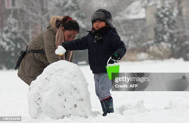 Boy uses a bucket and spade to build a snowman in a park in Redhill in Surrey, south of London, on February 5, 2012 after heavy snow. Heavy snow...