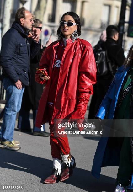 Guest is seen wearing a red coat red pants, cowboy boots and diamond silver earrings outside the Chanel show during Paris Fashion Week A/W 2022 on...