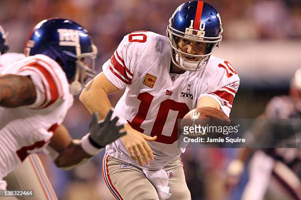 Quarterback Eli Manning of the New York Giants looks to hand off the ball to runningback Brandon Jacobs in the first quarter against the New England...