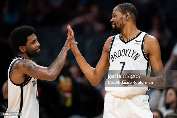 Kevin Durant congratulates Kyrie Irving of the Brooklyn Nets in the fourth quarter during their game against the Charlotte Hornets at Spectrum Center...