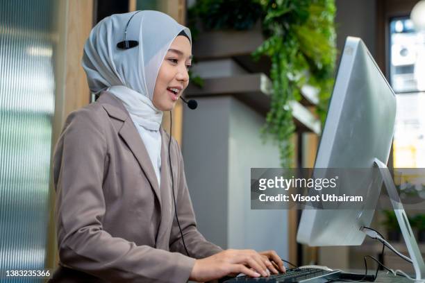 friendly operator woman agent with headsets working in a call centre,smiling support phone operator woman wearing hijab working in customer service. - religious service stock-fotos und bilder