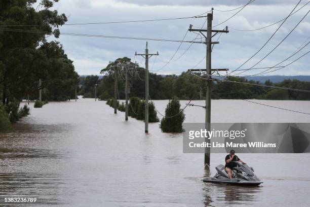 Man rides a jet ski in floodwaters along the Hawkesbury River in Windsor on March 09, 2022 in Sydney, Australia. Flood warnings and evacuation orders...