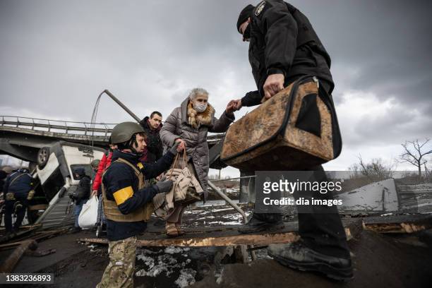 Ukrainians cross an improvised path along a destroyed bridge as residents continue to flee the city on March 8, 2022 on Irpin, Ukraine. Russia...