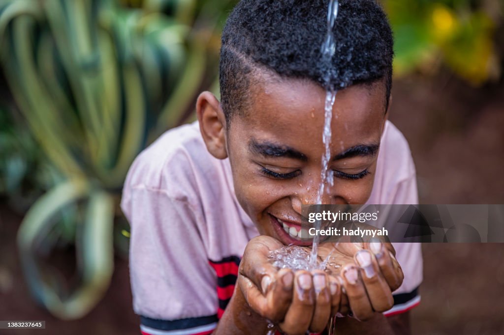 Afrikanischer Junge trinkt frisches Wasser, Ostafrika