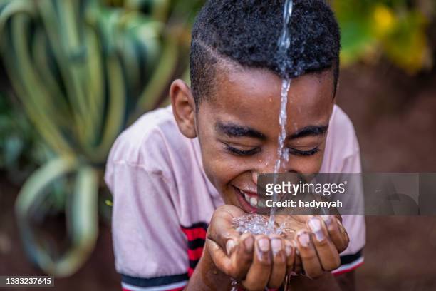 niño africano bebiendo agua dulce, áfrica oriental - agua dulce fotografías e imágenes de stock