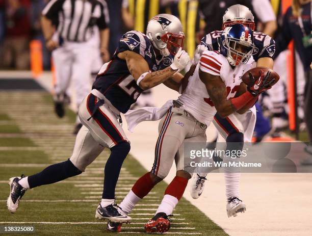 Mario Manningham of the New York Giants makes a catch on the sidelines against Patrick Chung and Sterling Moore of the New England Patriots for a...