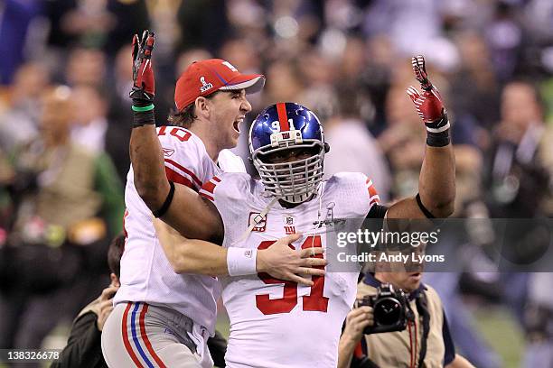 Eli Manning of the New York Giants celebrates with Justin Tuck after defeating the New England Patriots in Super Bowl XLVI at Lucas Oil Stadium on...