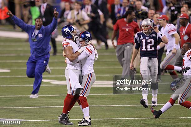 Osi Umenyiora and Steve Weatherford celebrate in front of Tom Brady of the New England Patriots after defeating the New England Patriots by a score...