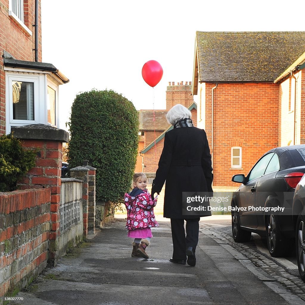 Girl holding red balloon with grandmother