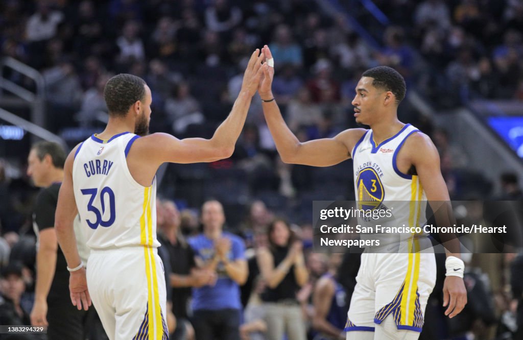 Stephen Curry and Jordan Poole high five during a timeout in the