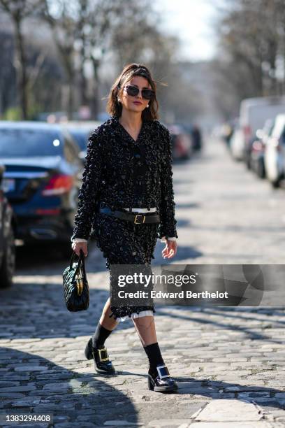 Alexandra Pereira wears sunglasses, large pearl earrings, a black with embroidered large pearls striped pattern jacket from Miu Miu, a matching black...