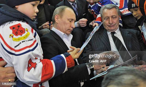 Picture taken on February 4 shows Russia's Prime Minister Vladimir Putin signing autographs for young ice hockey players during a visit to in the...