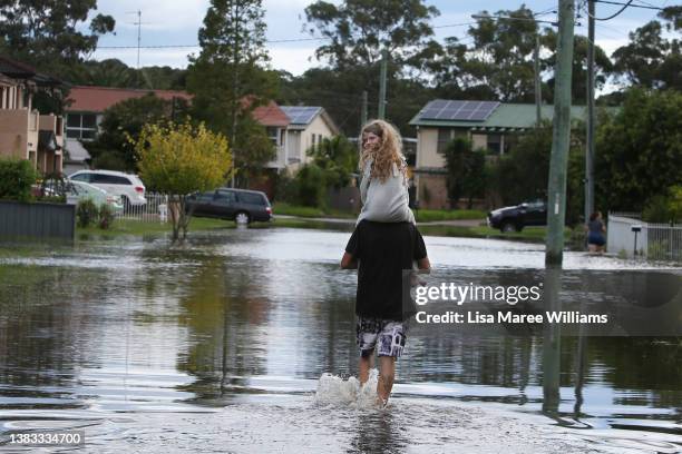 Gerry Rutterman and his daughter Kensey walk through floodwaters to return to their family home in Windsor on March 09, 2022 in Sydney, Australia....