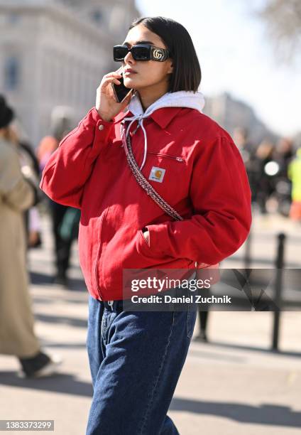 Model is seen wearing a red Carhartt jacket, blue jeans and Gucci sunglasses outside the Chanel show during Paris Fashion Week A/W 2022 on March 08,...