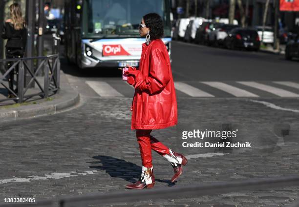 Guest is seen wearing a red coat, red pants and cowboy boots with white sunglasses and diamond earrings outside the Chanel show during Paris Fashion...