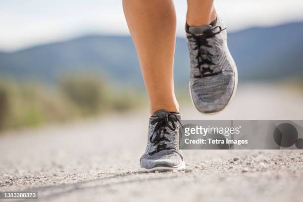 close-up of feet of woman jogging in desert landscape - running shoes close up stock-fotos und bilder