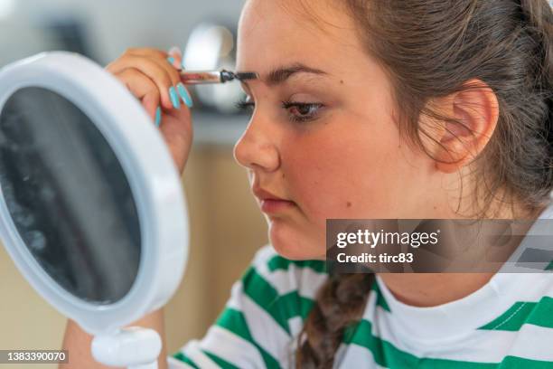 thirteen year old girl close up applying mascara to eyelashes - 12 13 girls stock pictures, royalty-free photos & images