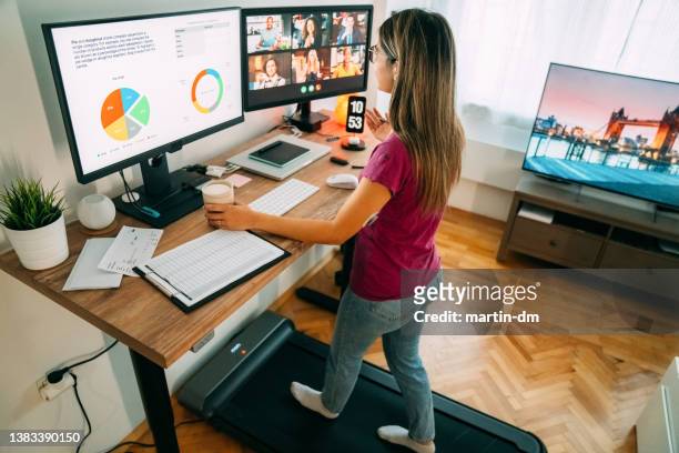 donna alla scrivania in piedi home office che parla in videochiamata aziendale - sport office foto e immagini stock