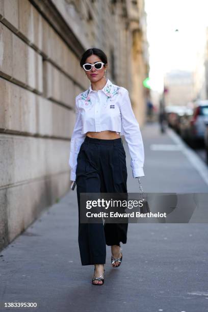 Mehrnaz Ansari wears white sunglasses, silver chain with a pearl pendant earrings, a white with embroidered pink and green pearls pattern cropped...