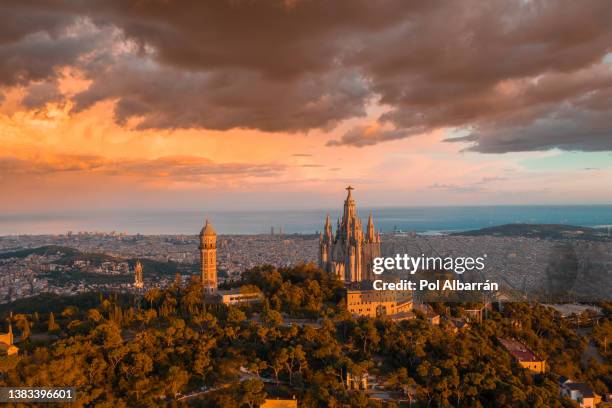 aerial view of sacred heart basilica on top of tibidabo near barcelona during sunset. - sagrada familia photos et images de collection